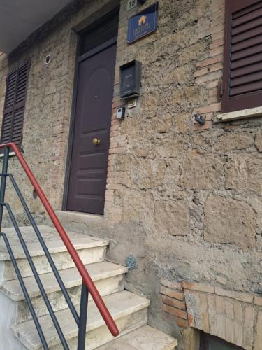 ein Backsteingebäude mit einer Tür und einer Treppe vorne in der Unterkunft ORVIETO BRICK HOUSE in Orvieto Scalo