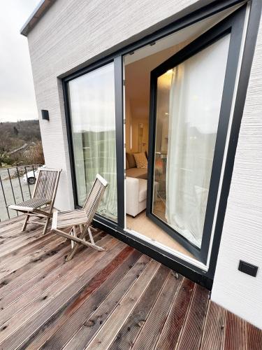 una terraza con 2 sillas y una ventana grande en FeWo Anders - Neubau mit Balkon im Bergischen Land, en Reichshof 