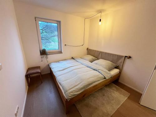 a small bed in a room with a window at FeWo Anders - Neubau mit Balkon im Bergischen Land in Reichshof 