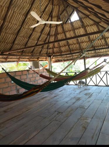 a hammock in a straw hut with a wooden floor at Cabaña hospedaje las Gaviotas in Moñitos