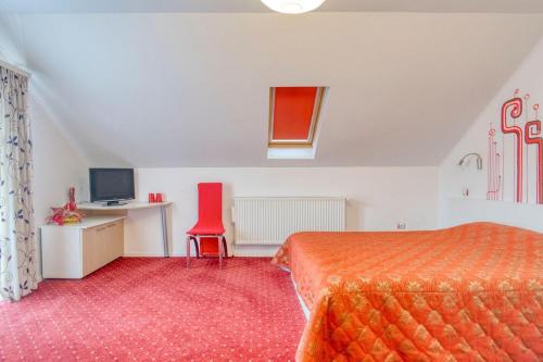 a bedroom with a bed and a desk and a red chair at Casa Preto E Branco in Moieciu de Jos
