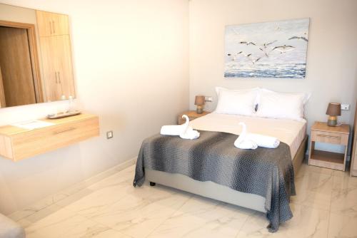 a bedroom with a bed with two swans on it at Beachfront Studio Kyma East ~ Crete's Hidden Gem in Kali Limenes