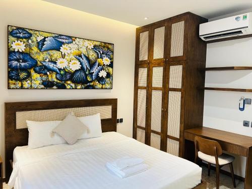 a bedroom with a bed and a desk and a painting at Lotus Home Cafe in Phú Quốc