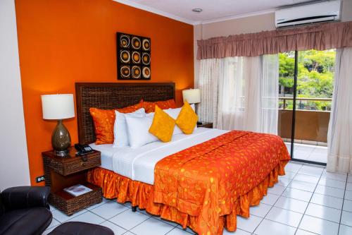 a bedroom with a large bed with an orange wall at Aparthotel Guijarros in Tegucigalpa