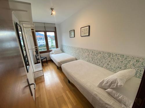 um pequeno quarto com uma cama e uma janela em Alojamiento Puente del Sella em Cangas de Onís