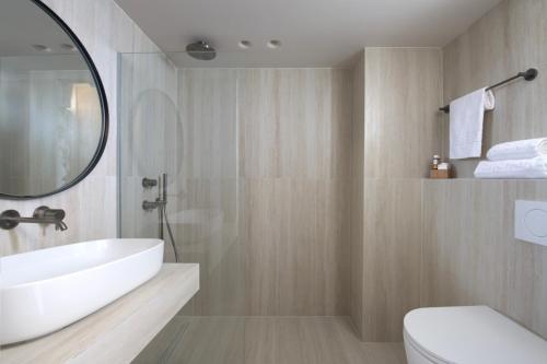 y baño con lavabo, aseo y espejo. en Argile Resort & Spa en Lixouri