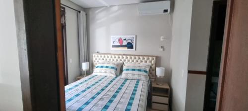 a bedroom with a bed with striped sheets and pillows at Apto na Bela Lagoa da Conceição in Florianópolis