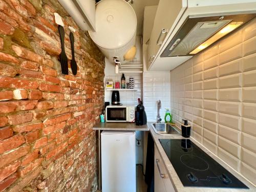 - une cuisine avec un mur en briques et un comptoir dans l'établissement Studio climatisé hyper-centre - 300m Basilique Saint Sernin, à Toulouse
