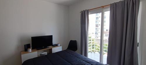 een slaapkamer met een bed, een televisie en een raam bij Zit Flat in Mar del Plata