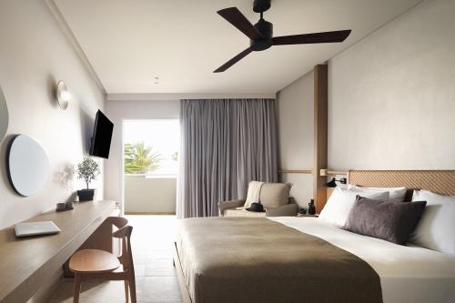 Habitación de hotel con cama y ventilador de techo. en Argile Resort & Spa, en Lixouri