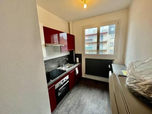 Elle comprend une petite cuisine avec des placards rouges et une fenêtre. dans l'établissement Le Lovely avec parking, à Amiens