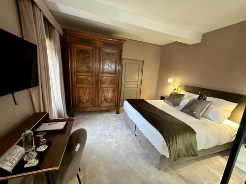 um quarto com uma cama, uma secretária e uma televisão em Les Villas du Domaine de Suzel em Vignieu