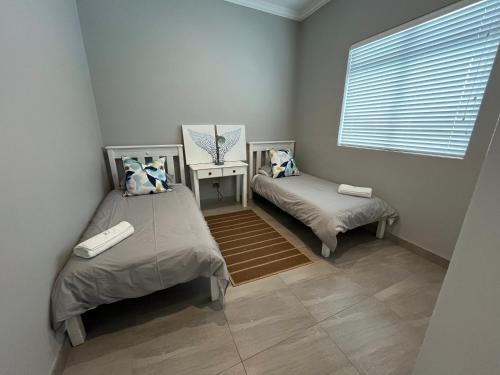 two twin beds in a room with a window at Unit 8 Alwil Ocean View Villa in Struisbaai