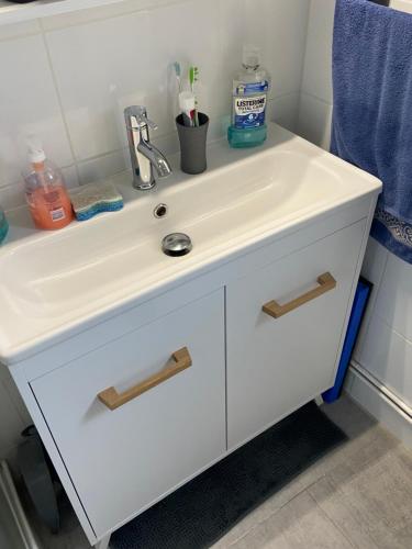 La salle de bains est pourvue d'une coiffeuse et d'un lavabo blanc. dans l'établissement T2 village naturiste Aphrodite, à Leucate