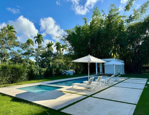 a swimming pool with chairs and an umbrella at Casa Coral in San Felipe de Puerto Plata