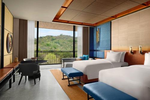 a hotel room with two beds and a balcony at TA’AKTANA, a Luxury Collection Resort & Spa, Labuan Bajo in Labuan Bajo