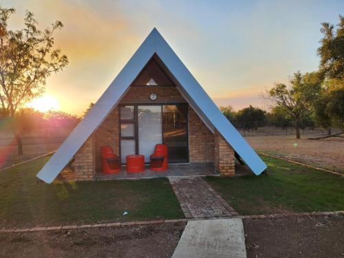 a small house with a triangular roof with red chairs at Mzimkhulu Ranch & Resort in Dinokeng Game Reserve