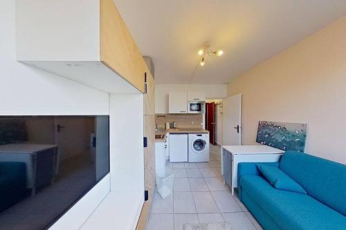 un salon avec un canapé bleu et une cuisine dans l'établissement Studio Cosy proche Gare de Poissy RER A, à Poissy