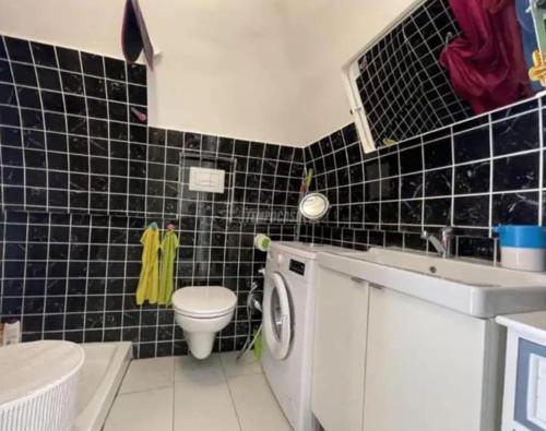 ein schwarz gefliestes Bad mit einem WC und einem Waschbecken in der Unterkunft Mary's house in Portici