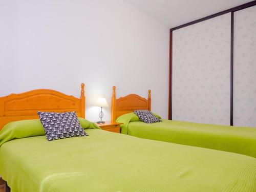 two beds in a room with green sheets at Chiclana.Balconera.1ªlínea playa in Chiclana de la Frontera