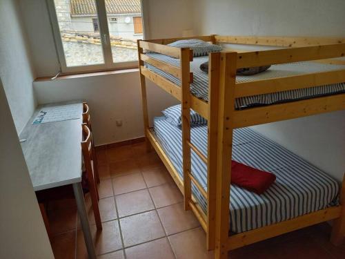 2 Etagenbetten in einem Zimmer mit einem Tisch und einem Fenster in der Unterkunft Agréable maison de village au calme in Sigean