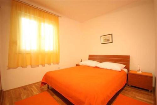 a bedroom with an orange bed and a window at Apartments Beverly in Omiš