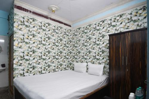 a bed in a bedroom with a floral wallpaper at OYO Blue Cherry Guest House in Ballygunge