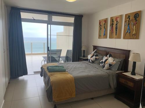 a bedroom with a bed with a view of the ocean at 304A Santorini -Margate RSA in Margate