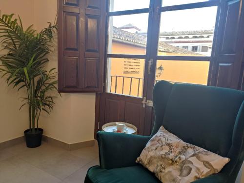 uma cadeira verde com uma almofada num quarto com uma janela em Granada Historic Center Apartment em Granada