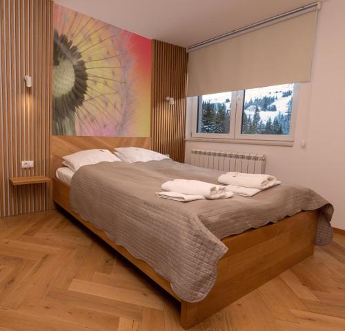 - une chambre avec un grand lit et des serviettes dans l'établissement Sunčani vrhovi, à Jahorina