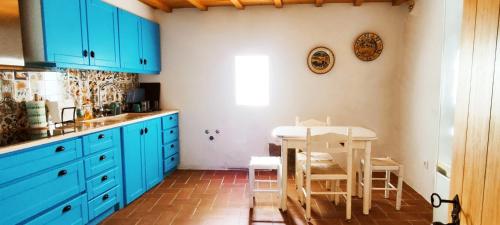 a kitchen with blue cabinets and a table and chairs at A Casa do Castelo in Estremoz