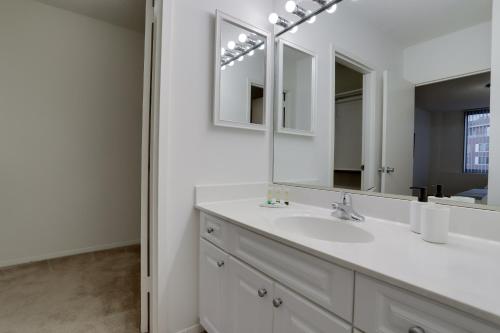 een witte badkamer met een wastafel en een spiegel bij Luxury Living at Crystal City's Condo in Arlington