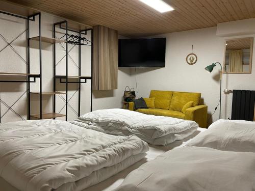 um quarto com duas camas e um sofá amarelo em Weitblick auf Berg, Wald und Wiese em Schmallenberg