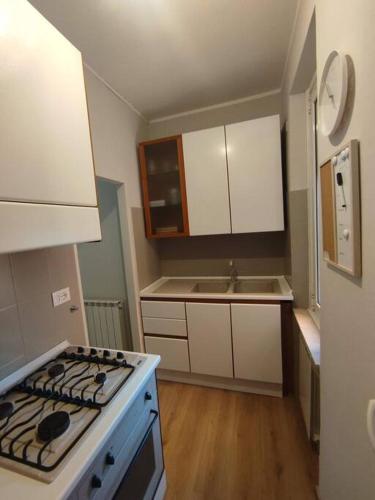 a kitchen with white cabinets and a stove top oven at CasaTelù - a due passi dal centro storico in Cernusco sul Naviglio