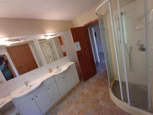 La salle de bains est pourvue de 2 lavabos et d'une douche. dans l'établissement Le Refuge, à Opont