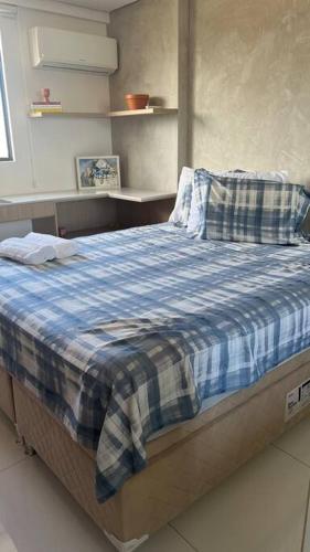 a bedroom with a bed with a blue plaid blanket at Studio a 300m da praia in Maceió