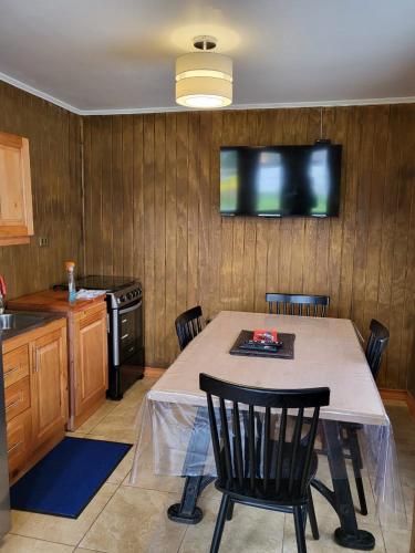錫斯內斯港的住宿－Cabañas kawi，厨房配有桌椅和墙上的电视