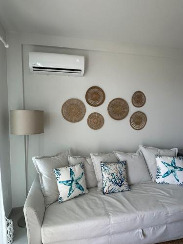 a living room with a white couch and some plates on the wall at White home Marzamemi in Marzamemi