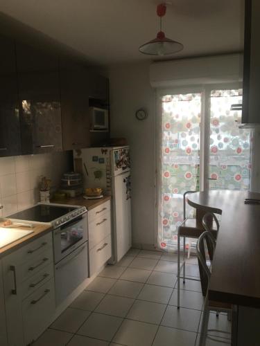 a kitchen with white appliances and a table and a window at CHAMBRES in Trappes