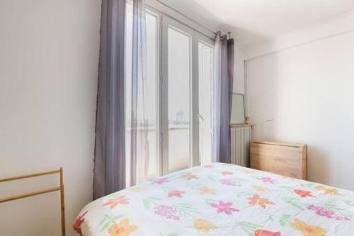 a bedroom with a bed with a floral bedspread and a window at Appart Plein Soleil Seine Paris 5ème Jardin Plantes in Paris