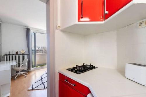 a kitchen with red cabinets and a stove top oven at Appart Plein Soleil Seine Paris 5ème Jardin Plantes in Paris