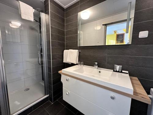 a bathroom with a sink and a shower and a mirror at Hotel Nap in West-Terschelling