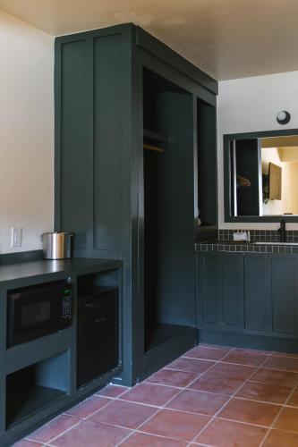 a kitchen with dark green cabinets and a mirror at Hummingbird Inn in Ojai