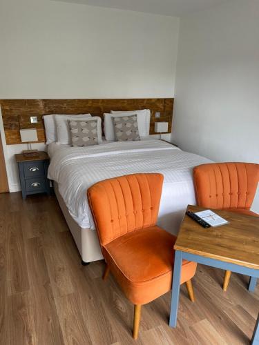 a bedroom with a bed with orange chairs and a table at Whitemoss Lodge in Dunning