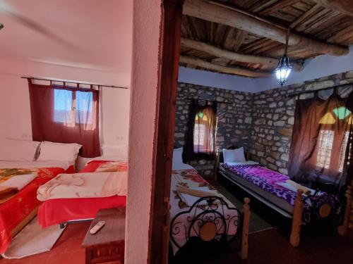a bedroom with two beds and a stone wall at Auberge Restaurant Telouet in Telouet