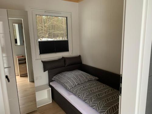a small bed in a small room with a window at Na Skraju Lasu Bielinek in Cedynia