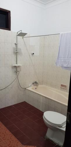 ein Badezimmer mit einer Badewanne, einem WC und einem Waschbecken in der Unterkunft Hotel pondok putri in Batukaras
