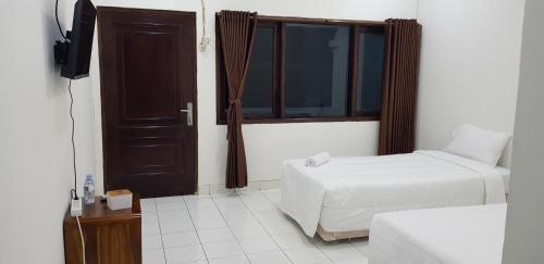 Schlafzimmer mit einem Bett, einem Fenster und einem TV in der Unterkunft Hotel pondok putri in Batukaras
