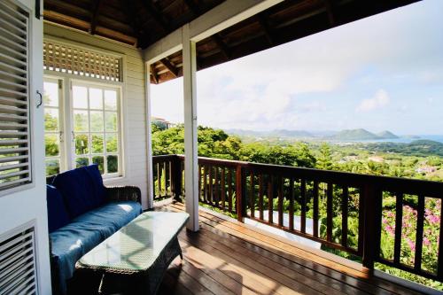a balcony with a couch and a view of the mountains at Hummingbird Villa - Tropical 3 bedroom Villa with Panoramic Views home in Cap Estate