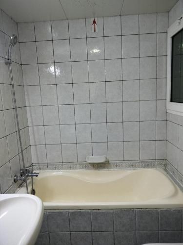 Hussaini Home في أبوظبي: حوض استحمام أبيض في حمام من البلاط